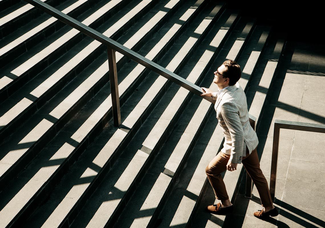 professional man in suit walking up stairs to office building